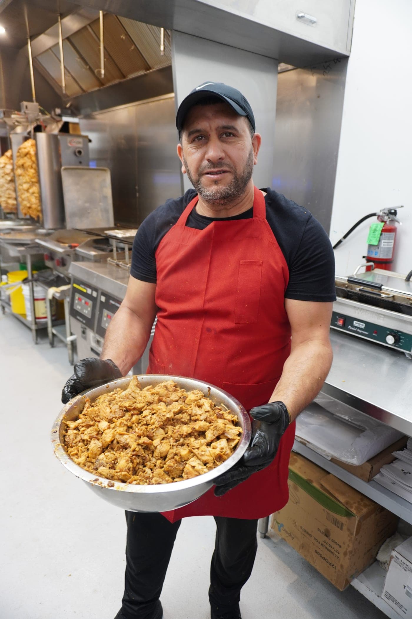 A tray of chicken carved off the spit, held up in the kitchen